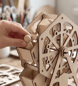 A hand playing with a custom wooden craft kit